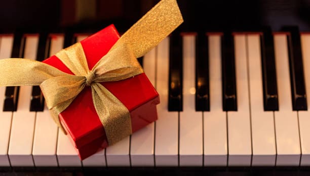 Red gift box on a classical piano keyboard, above view